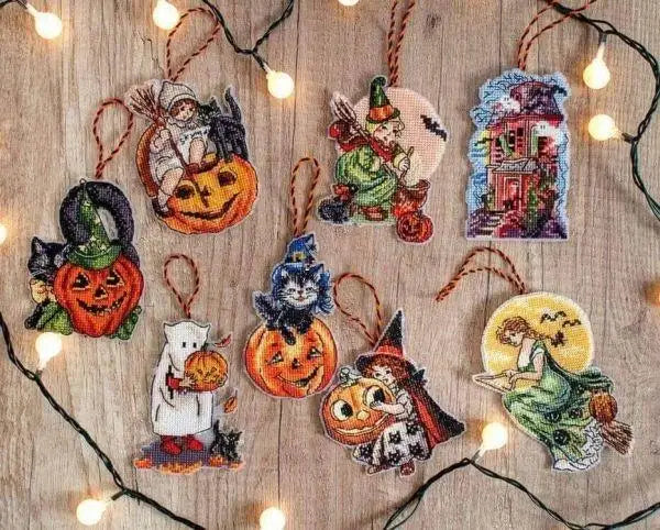 Halloween-themed embroidered ornaments on a wooden surface with string lights.