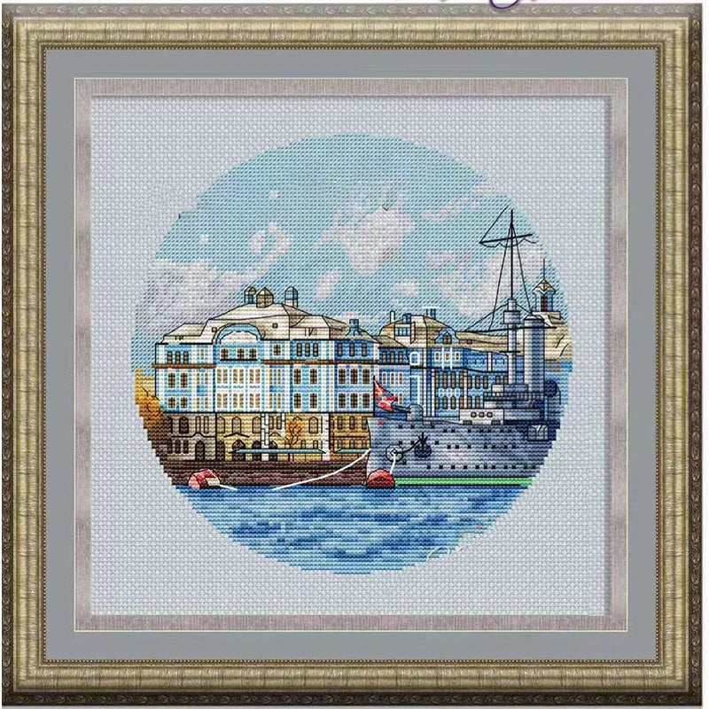 Cross-stitched cityscape with buildings and a ship on a white background