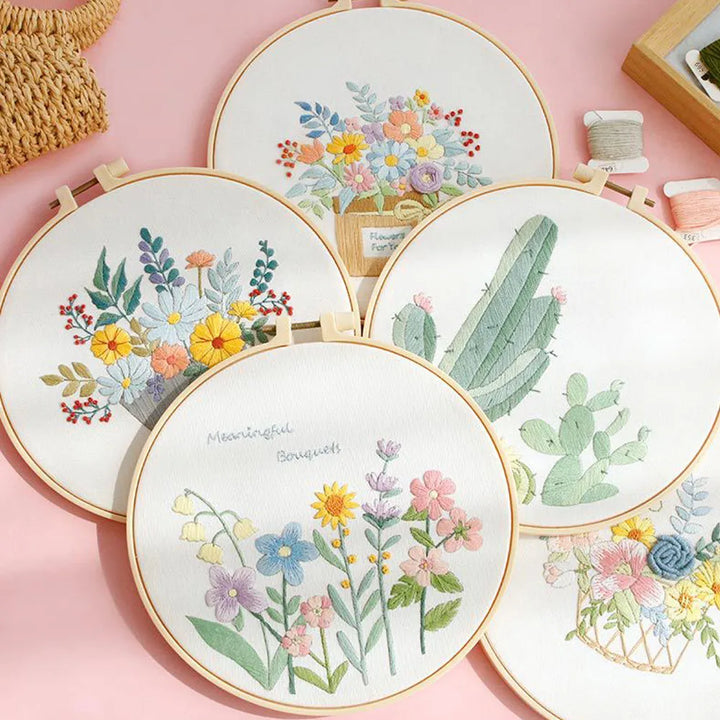 Embroidery hoops with floral and cactus designs on a pink background