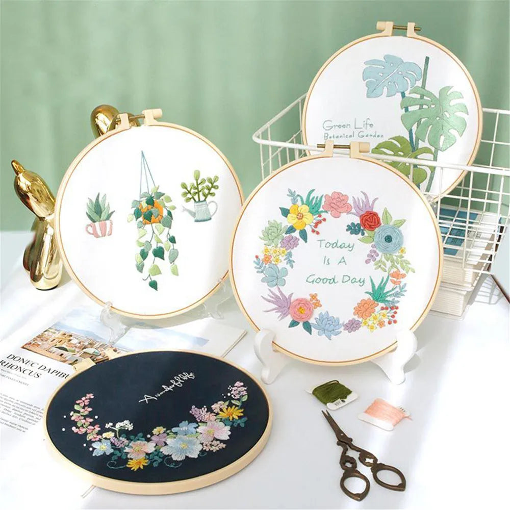 Embroidery hoops with floral designs on a white surface with a green background
