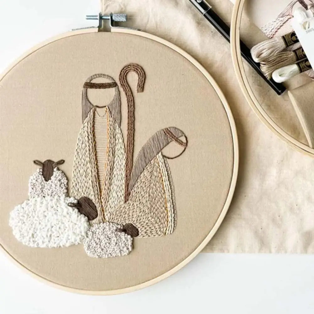 Embroidery hoop with a nativity scene design on beige fabric.