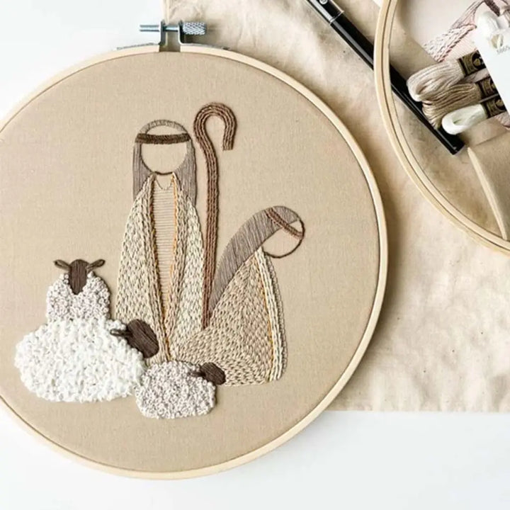 Embroidery hoop with a nativity scene design on beige fabric.