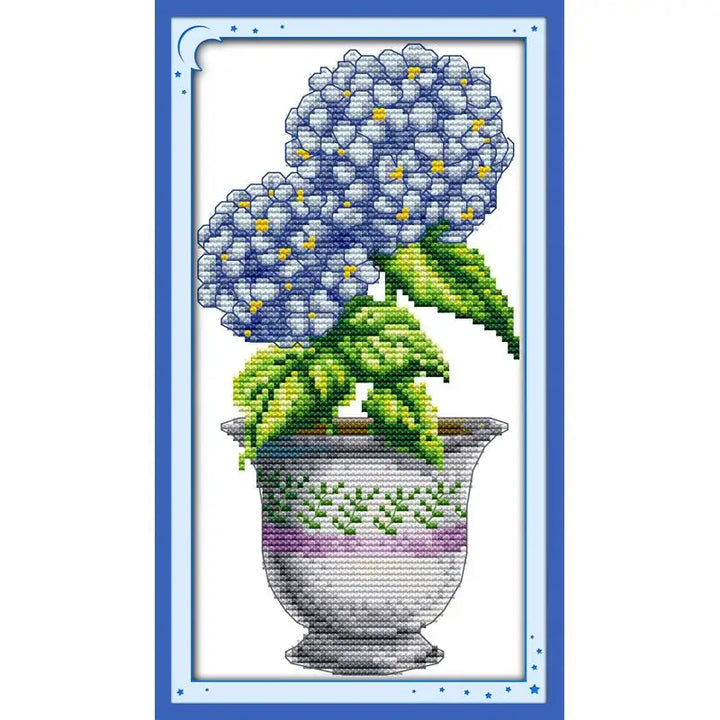 Cross-stitched design of a pot with blue flowers and green leaves on a white background.