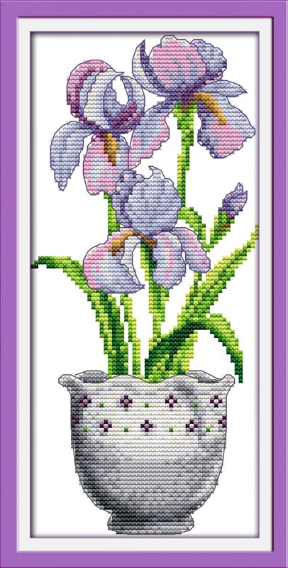 Cross-stitched design of purple flowers in a pot with a white border and purple frame.