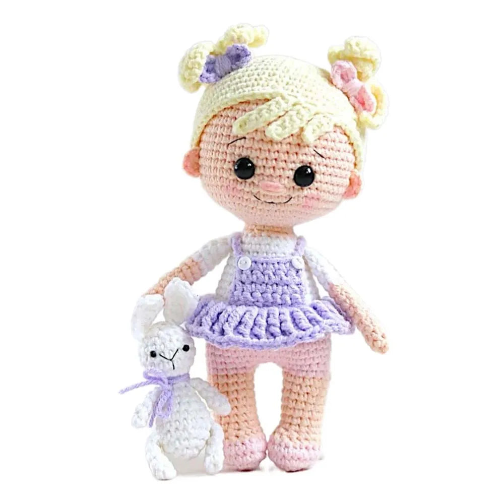 Crocheted doll with blonde hair and a small white rabbit toy on a white background