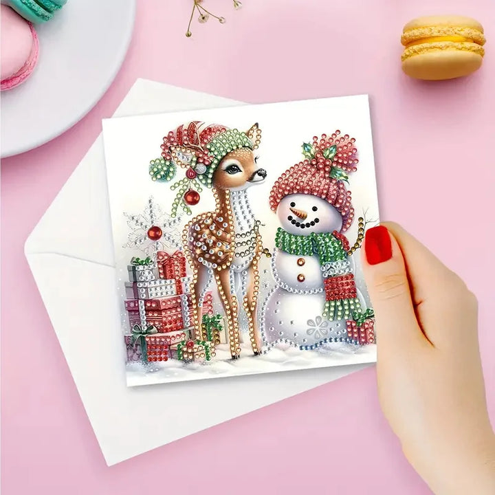 Christmas-themed card with a deer and snowman on a pink surface with macarons.