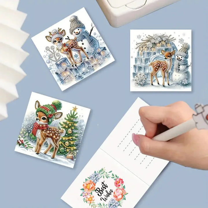 Set of diamond painting cards with Christmas-themed designs on a blue surface.