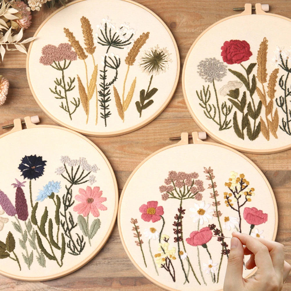 Four embroidery hoops with floral patterns on a wooden surface.