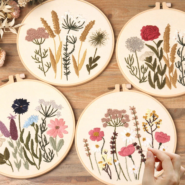 Four embroidery hoops with floral patterns on a wooden surface.