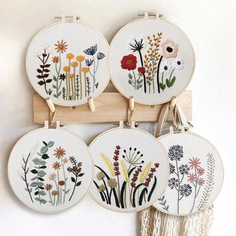 Set of embroidered hoop art with floral designs on a wooden stand.