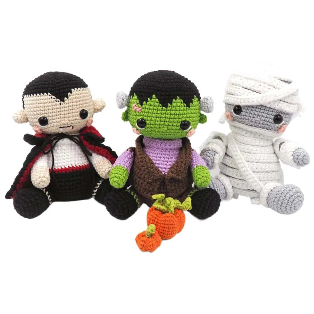 Three crochet dolls resembling a vampire, Frankenstein's monster, and mummy on a white background