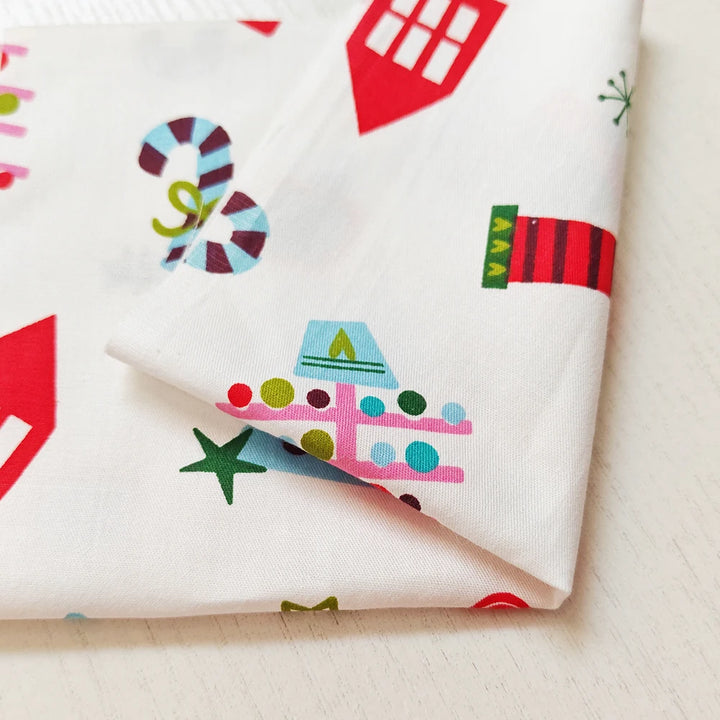 Roll of fabric with colorful house and starfish pattern on a white background