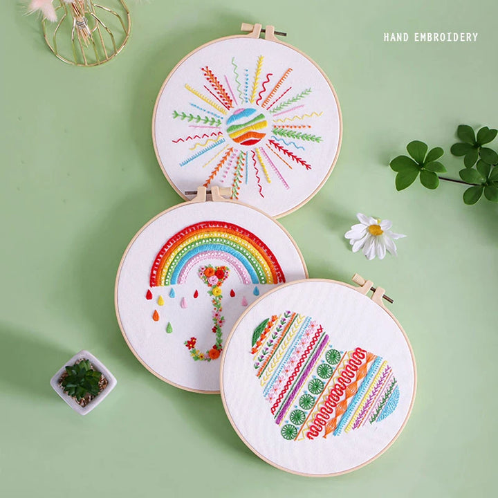 Three hand-embroidered hoops with colorful designs on a green background