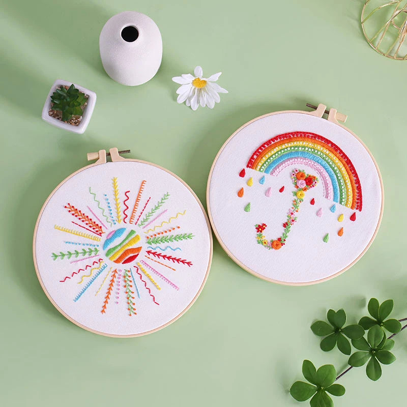 Two embroidery hoops with colorful designs on a green background
