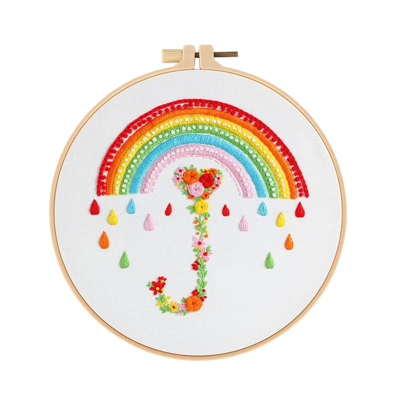 Embroidery hoop with a colorful rainbow and floral design on a white background