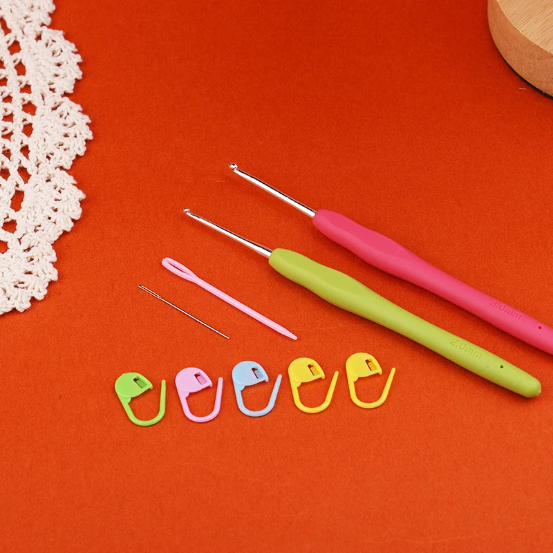 Set of crochet hooks and colorful stitch markers on an orange background with a white lace doily.