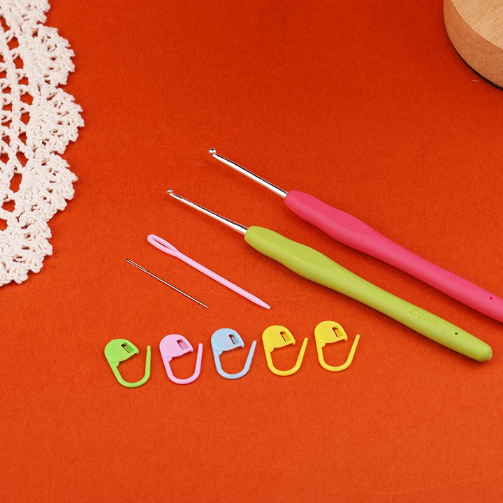 Set of crochet hooks and colorful stitch markers on an orange background with a white lace doily.