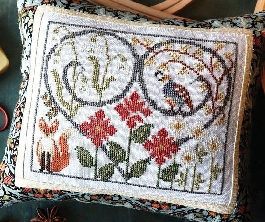 Embroidered pillow with floral and animal design on a fabric background