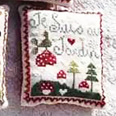 Cross-stitched design with mushrooms, trees, and text on a fabric background