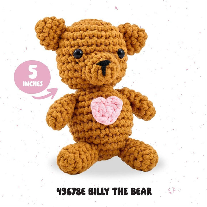 Crocheted bear toy with a pink heart on a white background