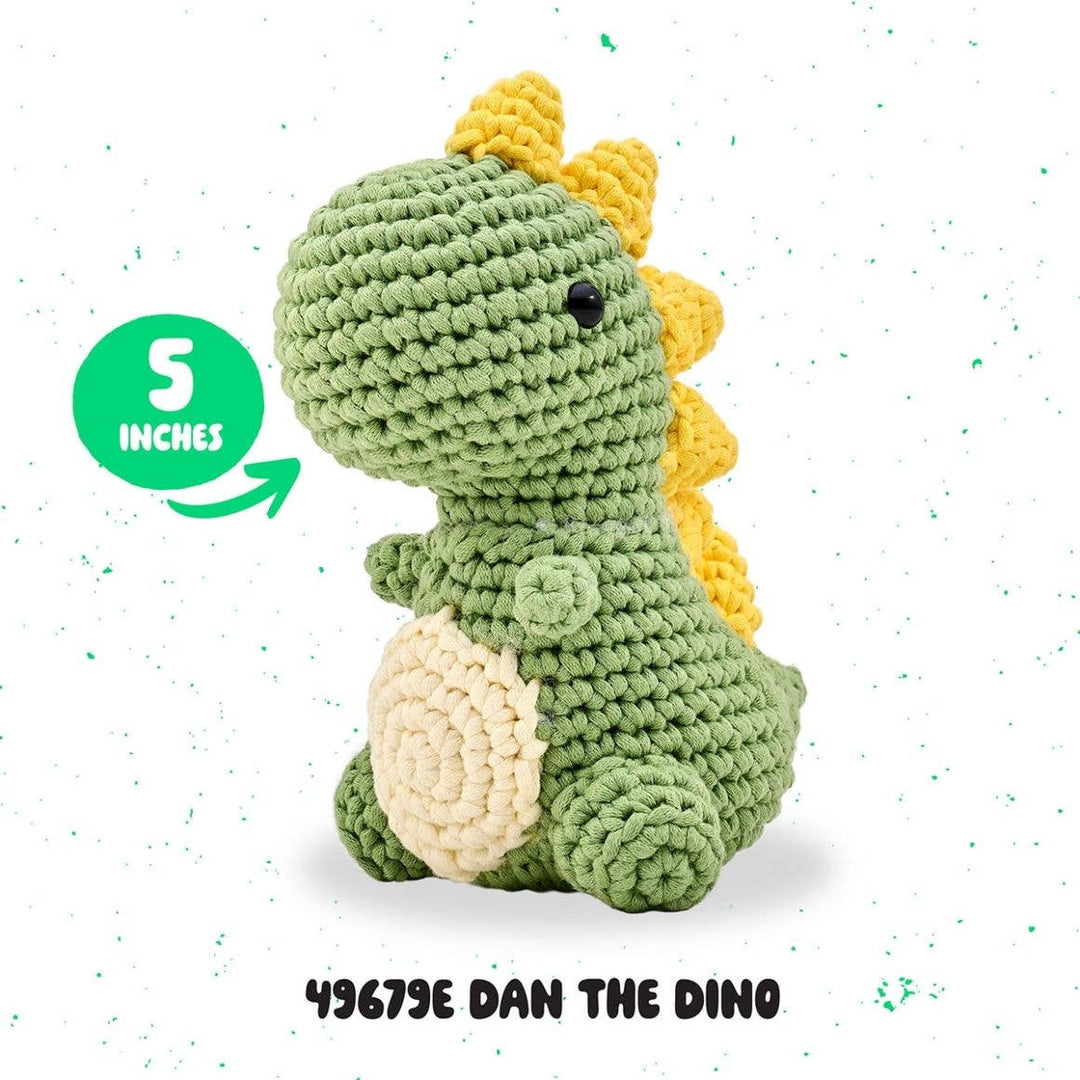 Crocheted dinosaur toy with green body, yellow spikes, and beige belly on a white background.