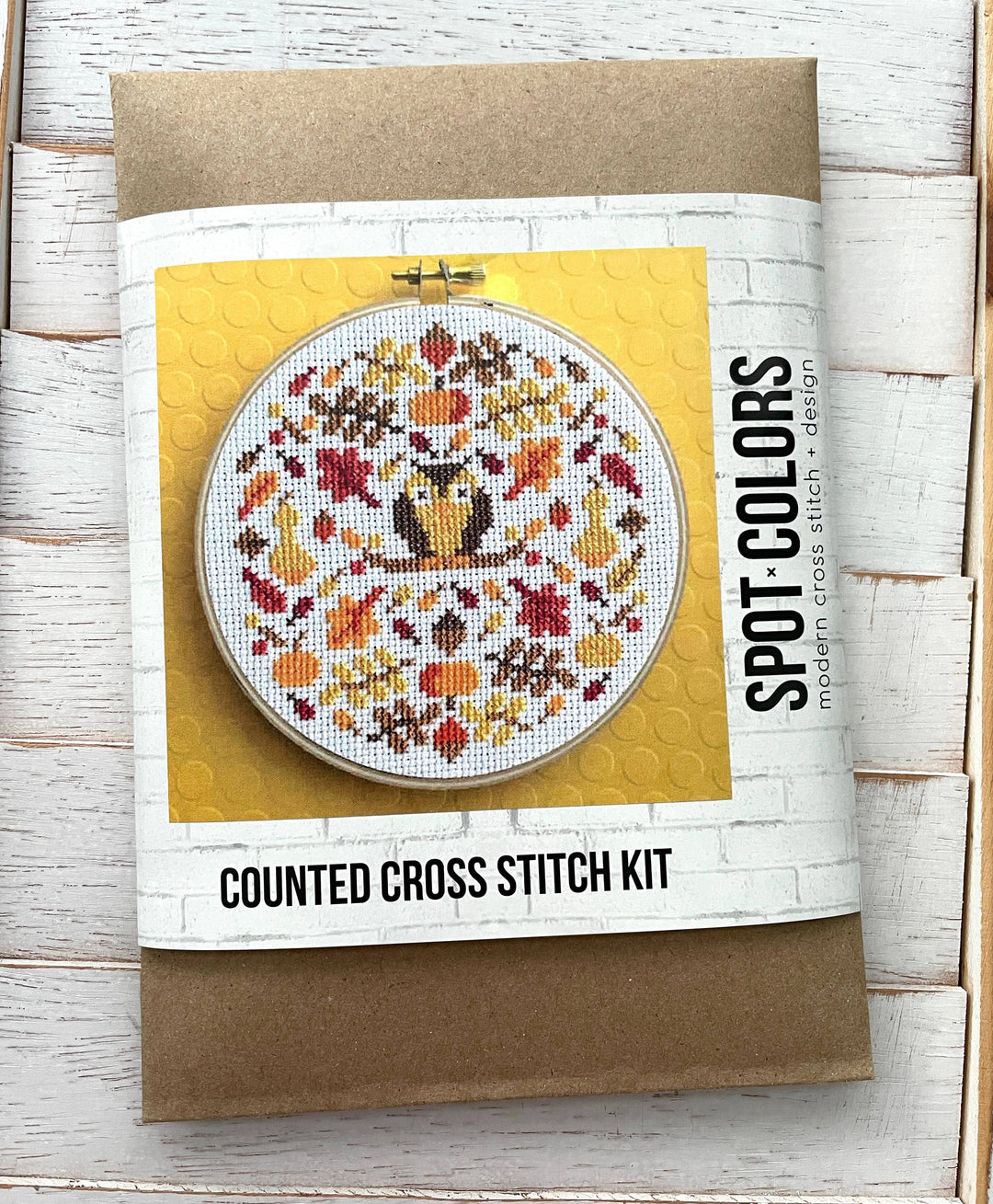 Counted cross stitch kit with owl design on a wooden surface