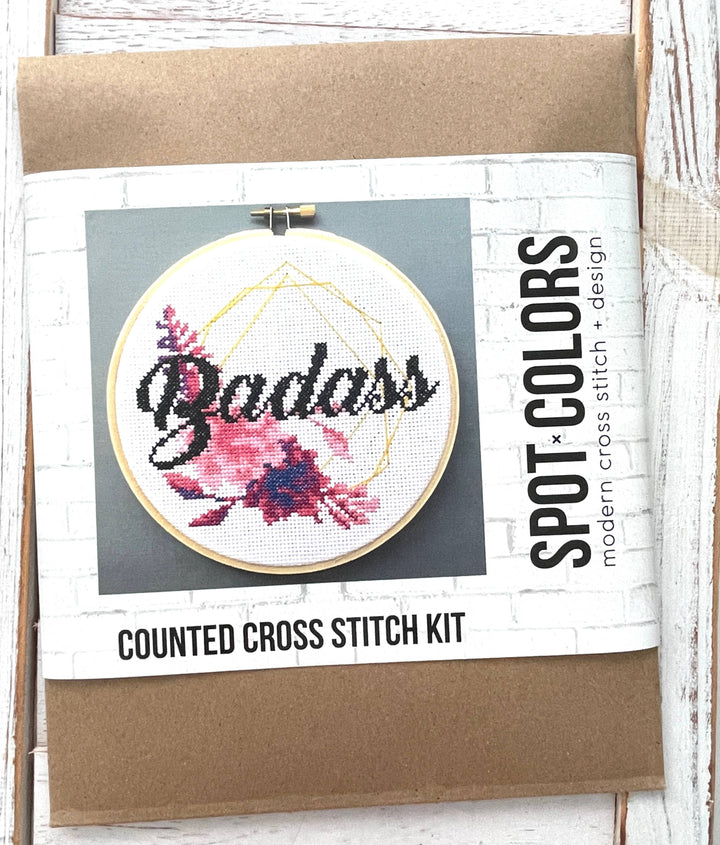 Counted cross stitch kit with 'Badass' design on a cardboard backing