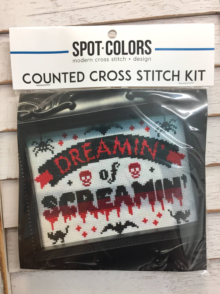 Counted cross stitch kit with 'Dreamin' of Screamin'' design in packaging on a wooden surface.
