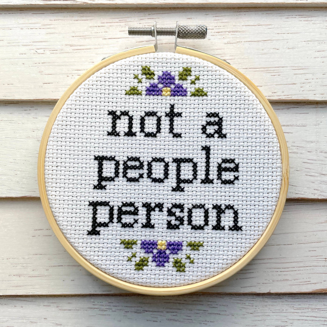 Cross-stitched hoop with 'not a people person' text on a wooden background