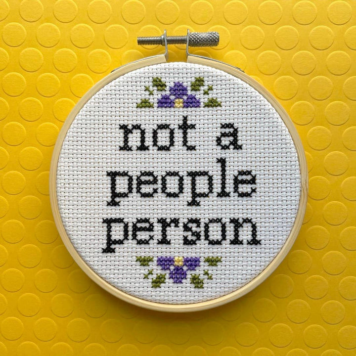Cross-stitched hoop with 'not a people person' text on a yellow background
