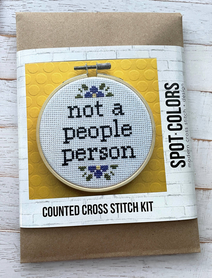 Counted cross stitch kit with hoop and fabric on a wooden surface