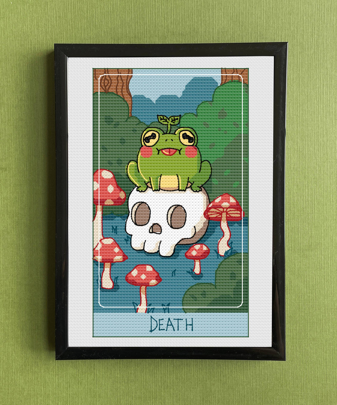 Framed artwork of a cartoon frog on a skull with mushrooms, labeled 'DEATH', against a green wall.