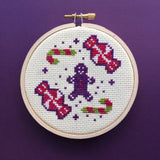 Cross-stitched gingerbread man and candy cane design on a purple background