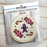 Cross stitch kit with gingerbread men and candy design on a wooden surface
