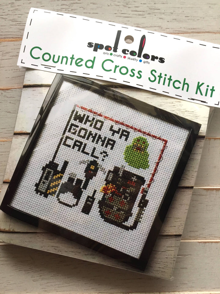 Cross stitch kit with 'Who ya gonna call?' design on a wooden surface
